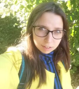 A brunette woman with glasses looks at the camera