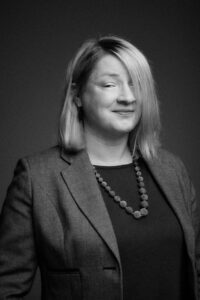 A woman with blonde hair in business dress in a black and white photo