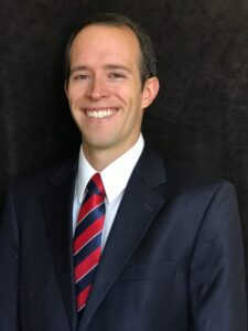 Patrick Monson Portrait A smiling man in a dark suit