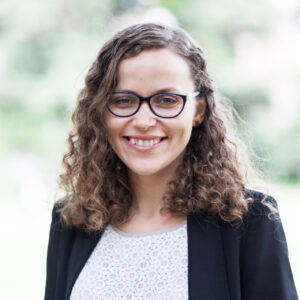 A smiling woman with glasses and curly hair