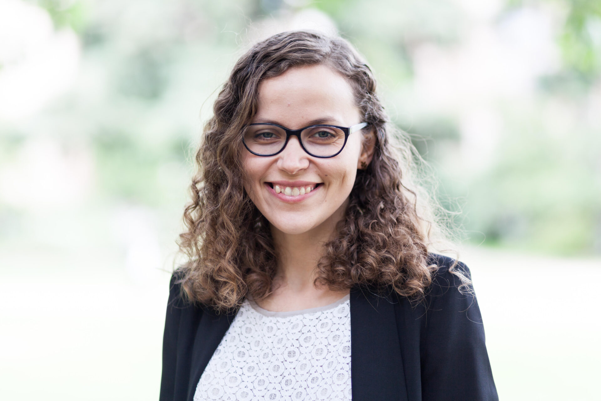 A smiling woman with glasses and curly hair