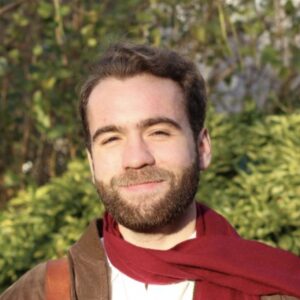 John Ellis grantee portrait copy A smiling man with a beard and a red scarf