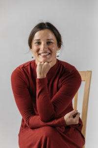 A smiling woman in a red dress sitting on a chair