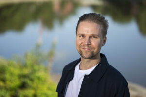 A smiling man in front of a lake